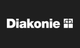Diakonie-Logo: Weißer Schriftzug „Diakonie“ mit stilisiertem Geschenkpaket auf schwarzem Hintergrund.