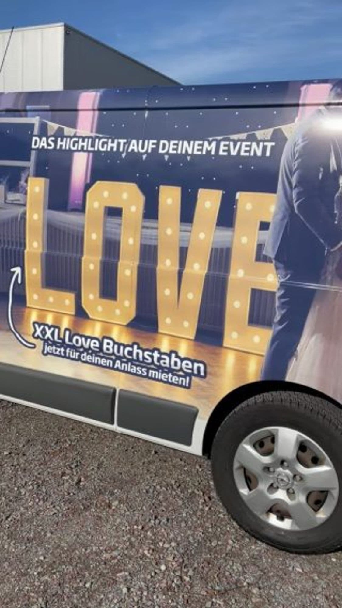 Großformatiger Fotodruck auf der Seite eines Transporters mit leuchtenden XXL-Buchstaben „LOVE“