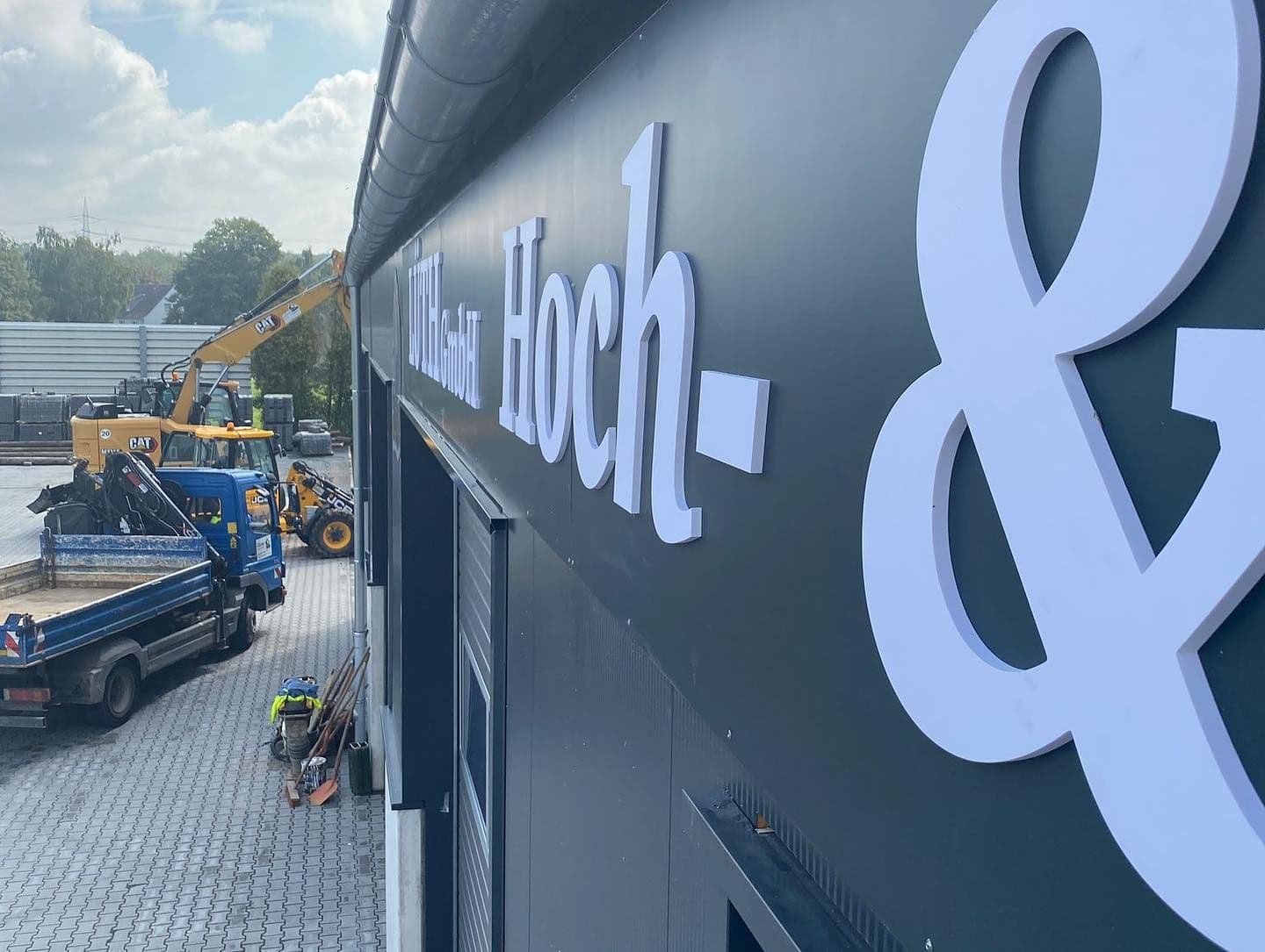Weiße 3D-Buchstaben „Hoch- &“ an der dunklen Fassade der LUTH GmbH Hoch- und Tiefbau