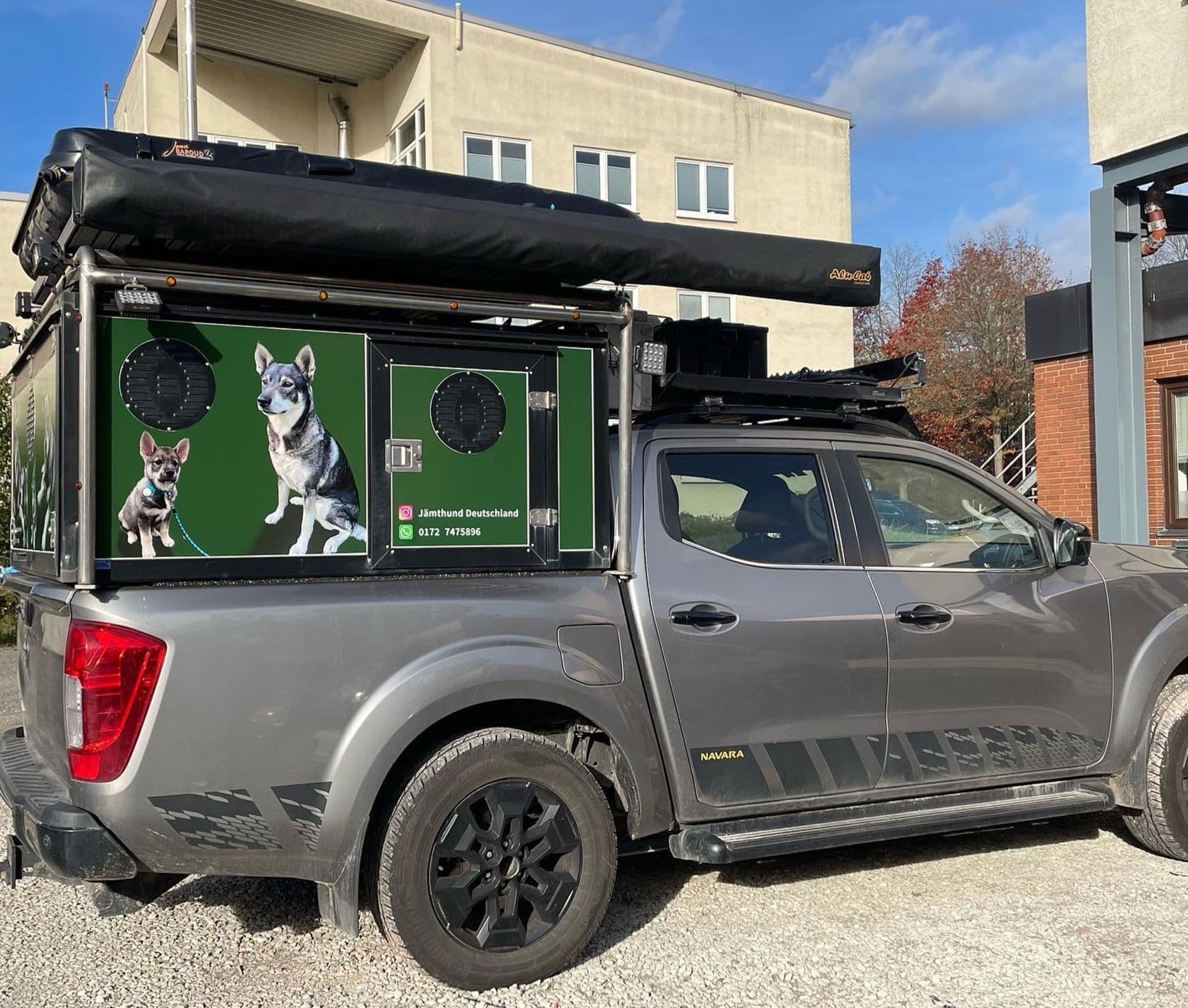 Grauer Pickup mit beschrifteter schwarzer Hundebox auf der Ladefläche