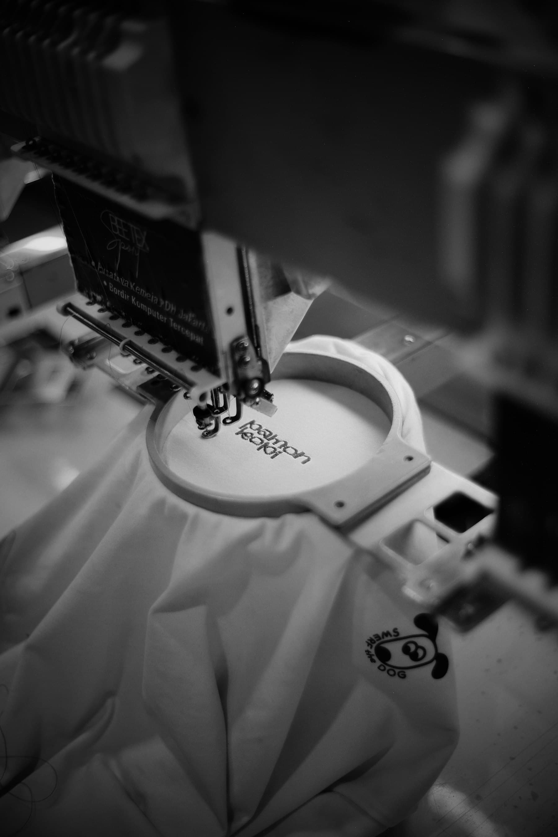 Stickmaschine stickt ein Motiv auf Stoff, Nahaufnahme in Schwarzweiß