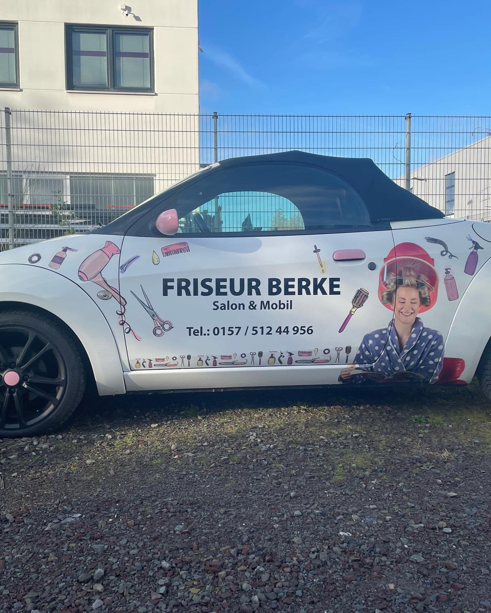 Weißes Auto mit „FRISEUR BERKE Salon & Mobil“ und einer lächelnden Frau unter einer Haube.