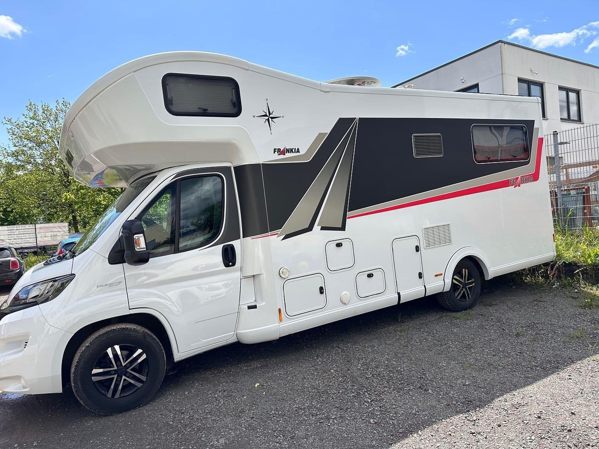 Weißes Wohnmobil mit schwarz-roter Designfolierung über die ganze Seitenfläche
