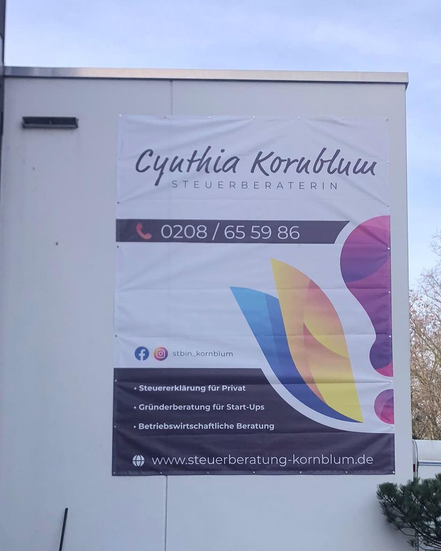 Bedruckte Werbeplane der Steuerberaterin Cynthia Kornblum an einer Hauswand